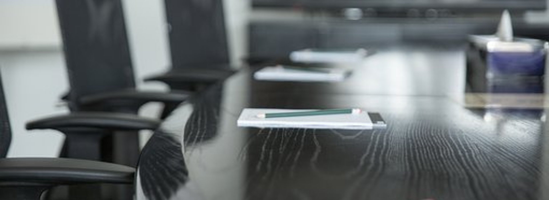 board room table and empty chairs with pad of paper and pen next to it