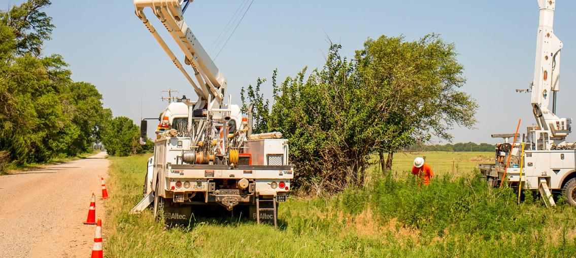 Electric utility trucks at the side of a dirt road